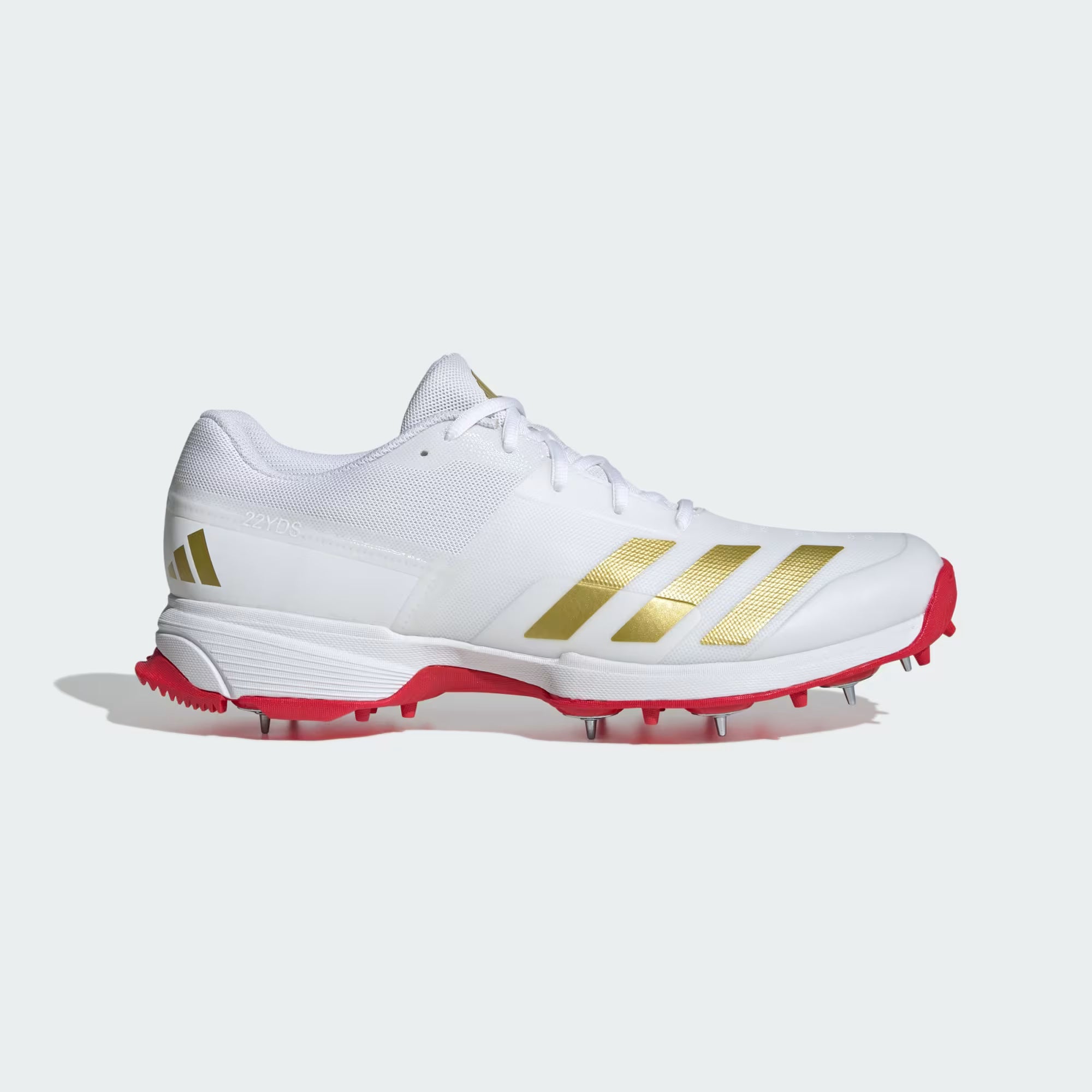 White athletic shoe with gold stripes and red soles on a white background