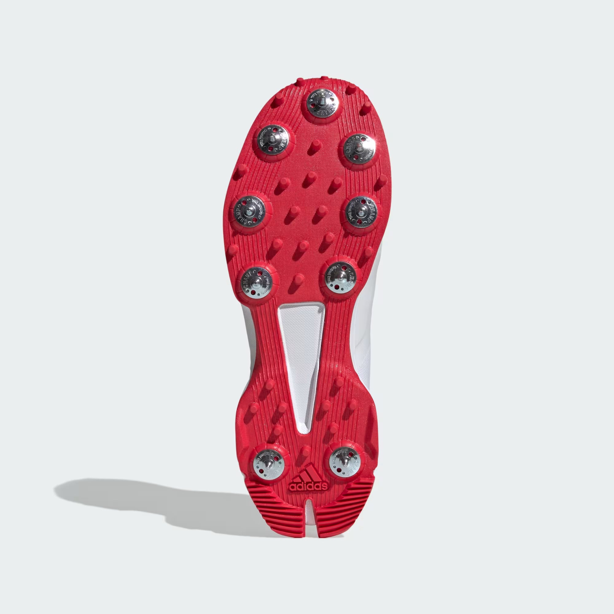 Red soccer cleat sole with metal studs on a white background