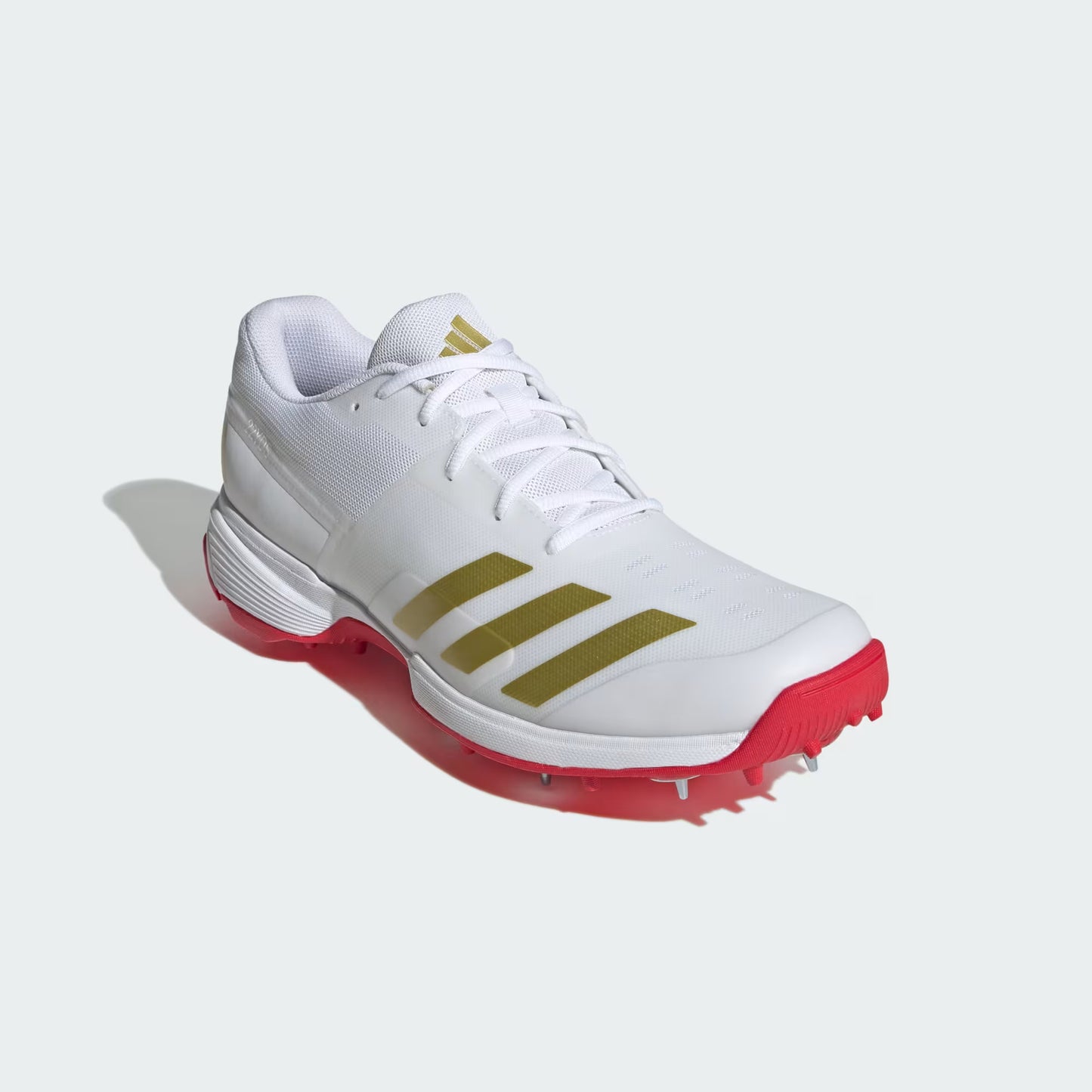 White golf shoe with gold stripes and red soles on a white background