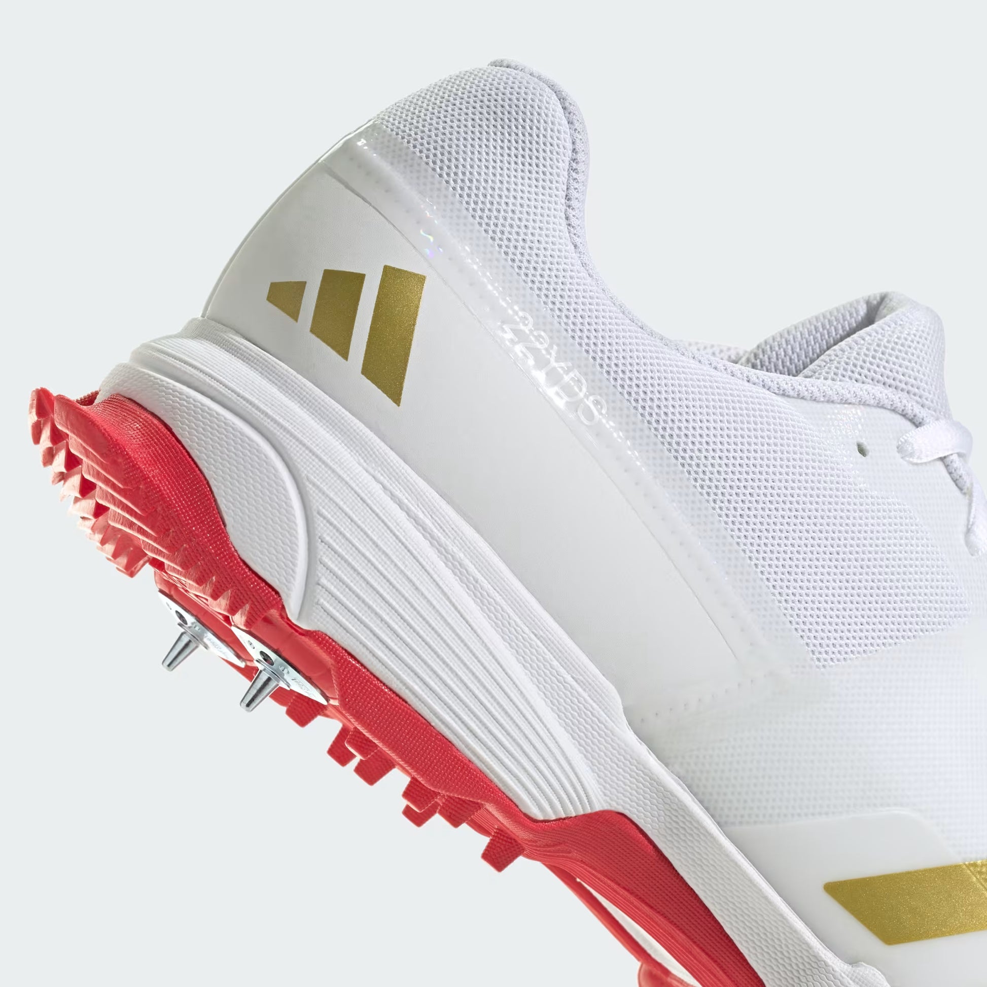White sports shoes with gold stripes and red soles on a white background