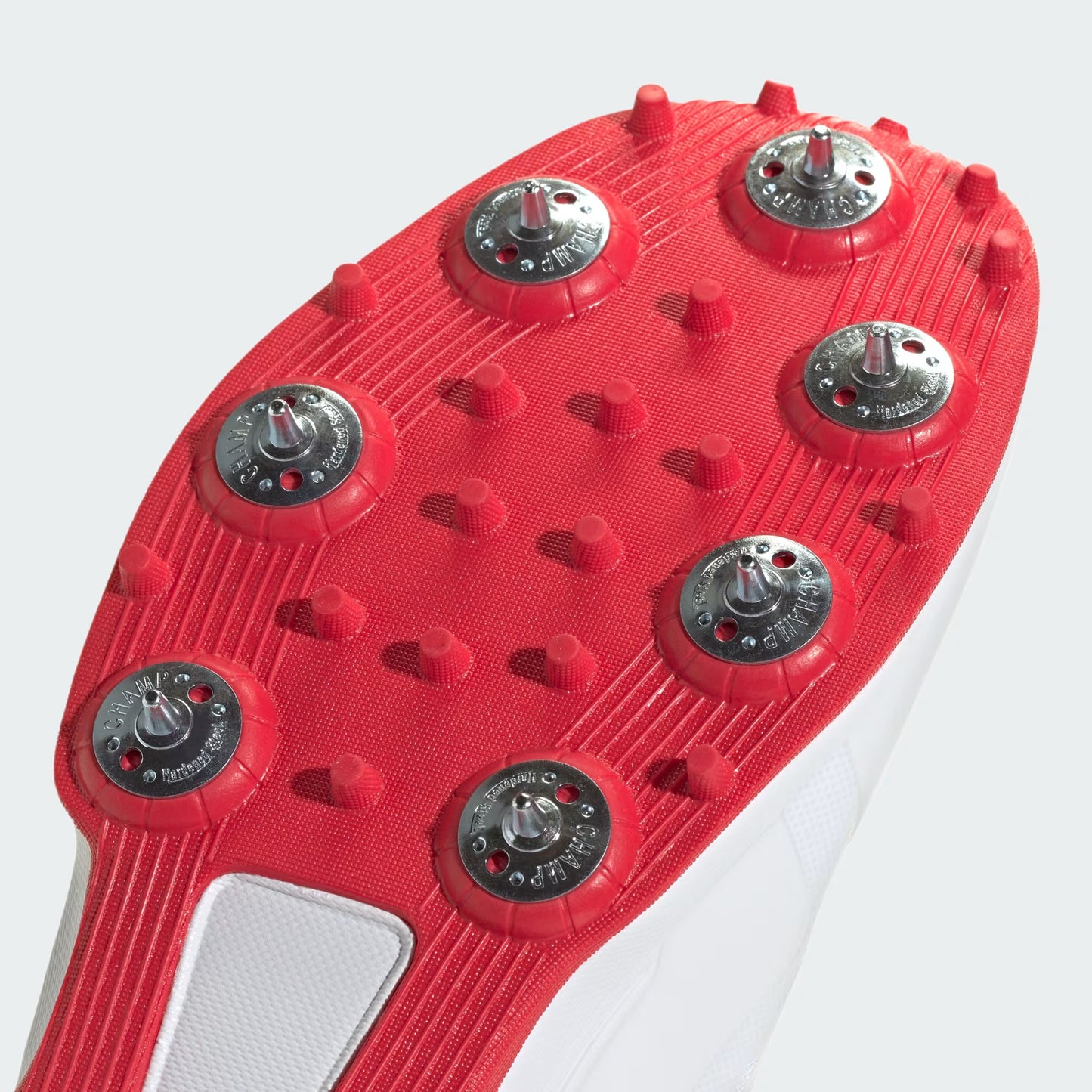Close-up of a red soccer cleat sole with tread pattern on a white background