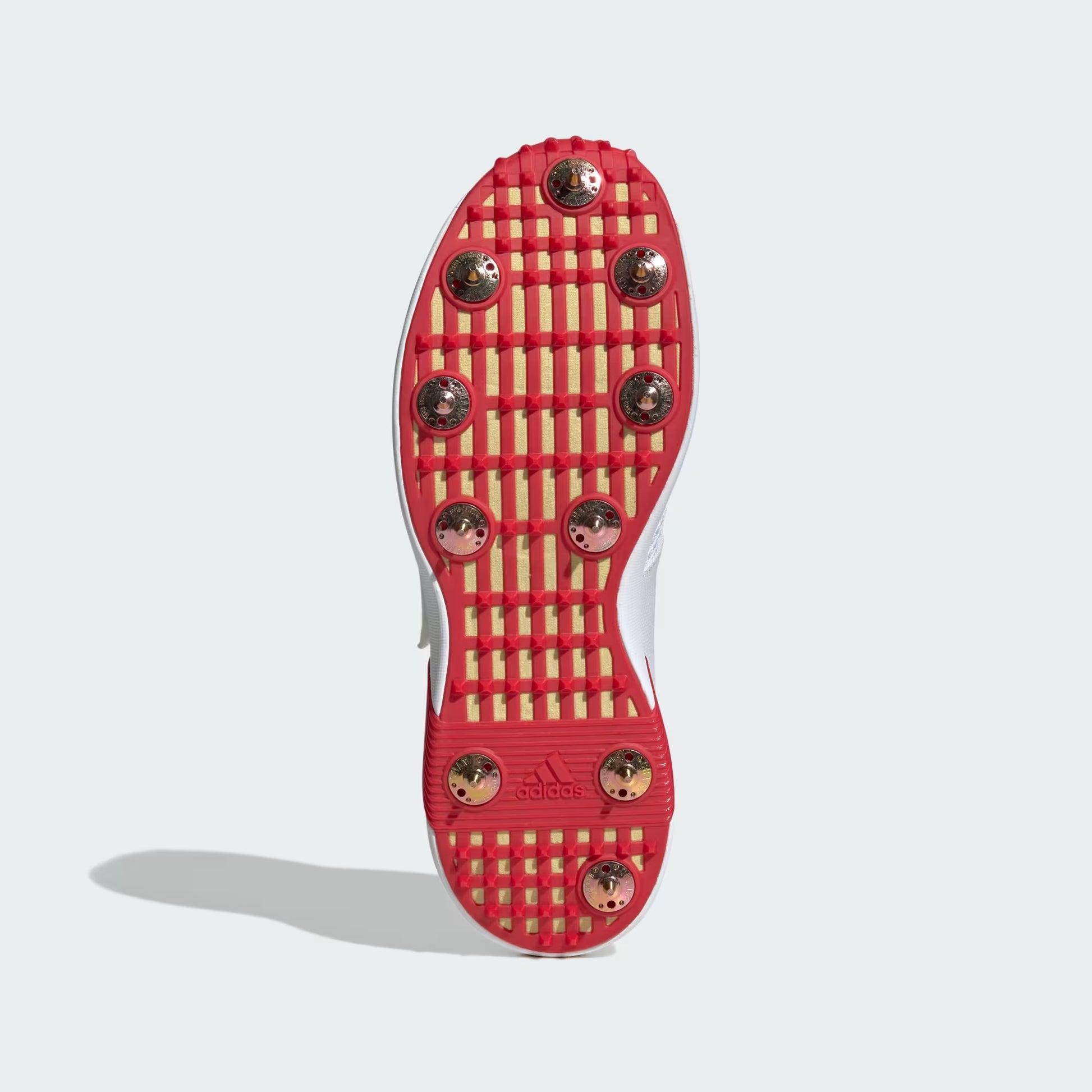 Red soccer cleat sole with gold studs on a white background