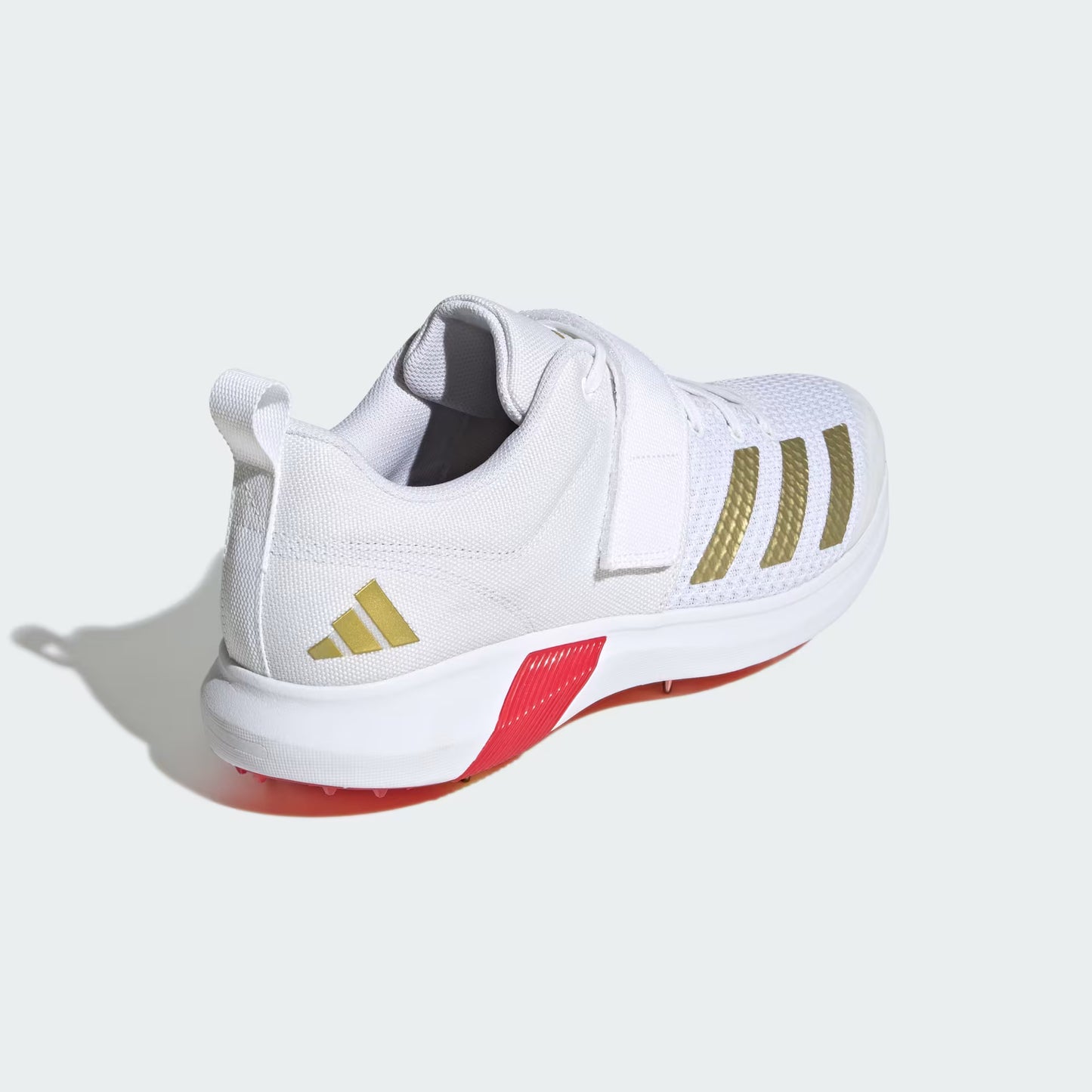 White athletic shoe with gold stripes and red sole on a white background