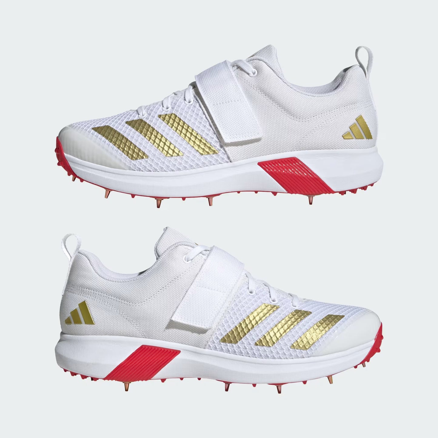 White athletic shoes with gold stripes and red accents on a white background